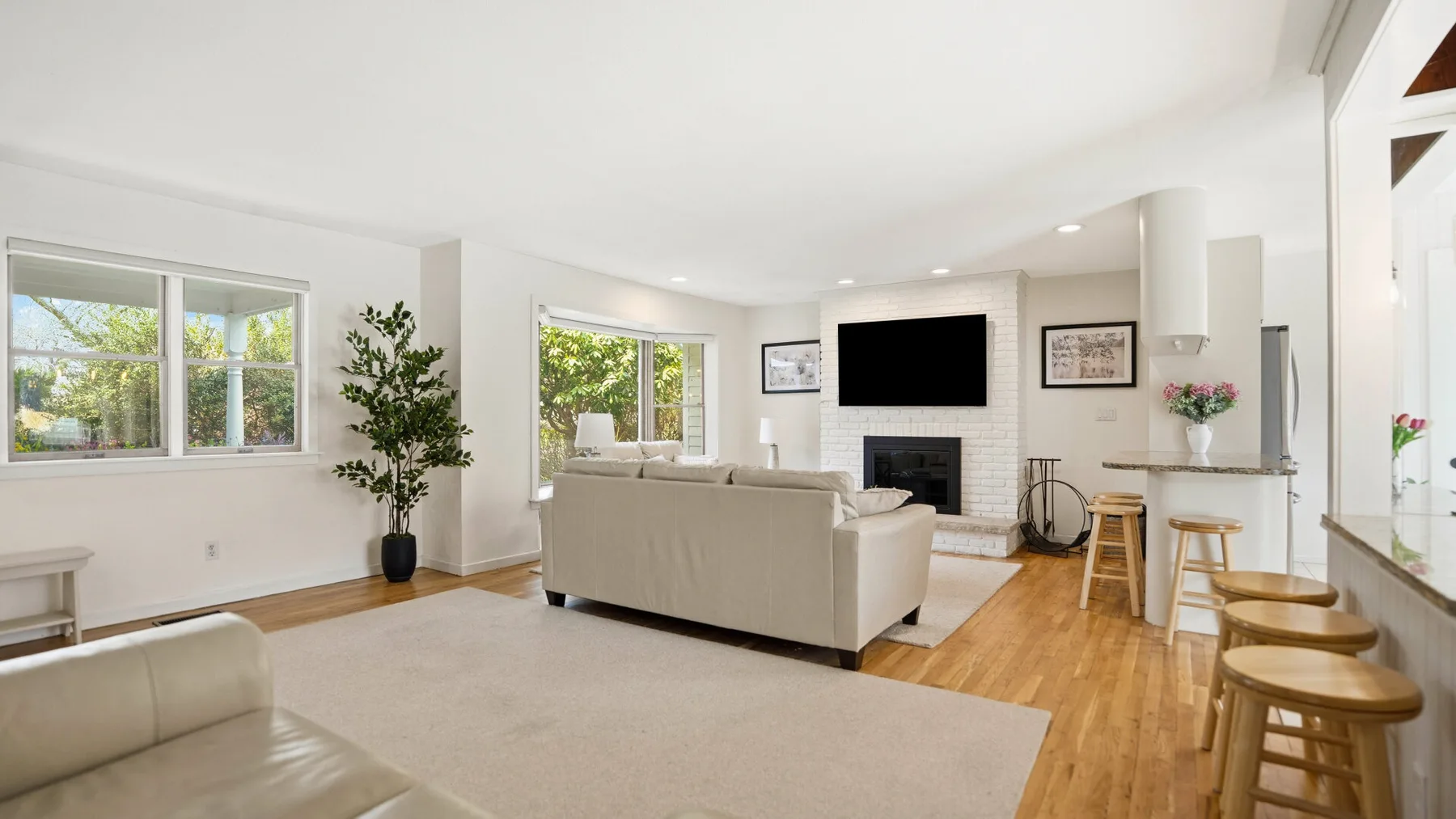 A bright living room with seating, a television, and a dining counter.