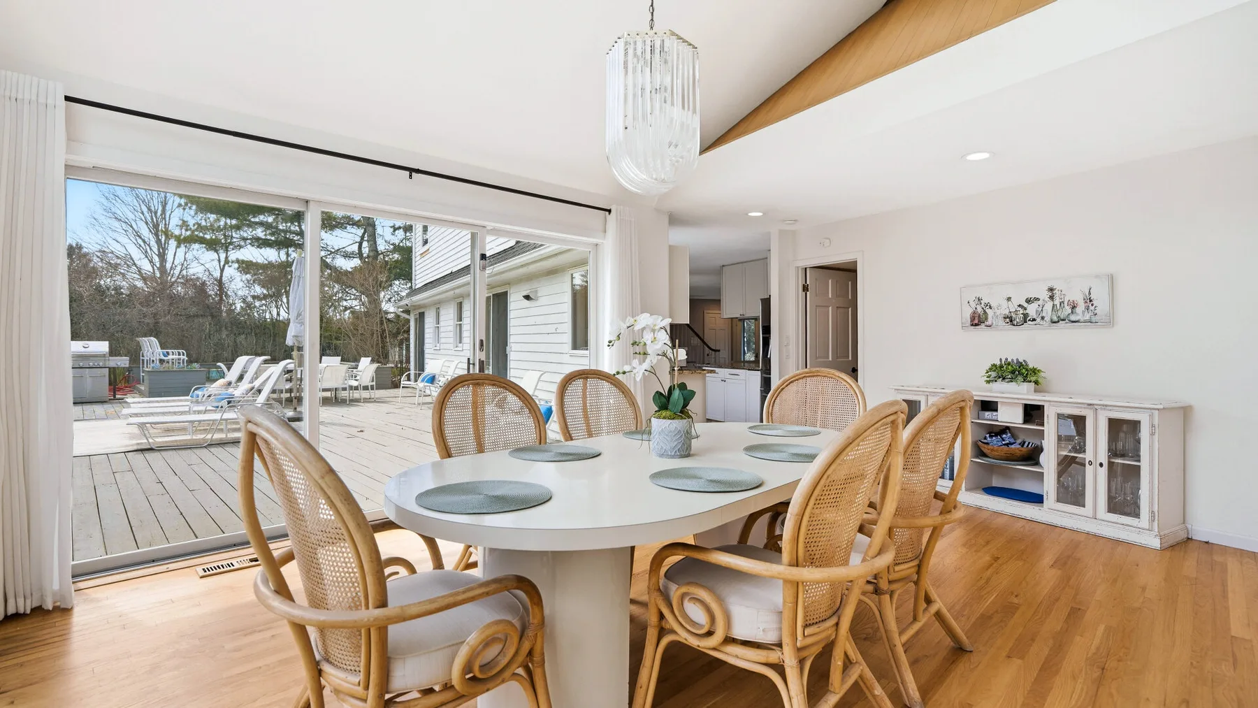A bright dining area with a round table and sliding glass doors opening onto a deck.