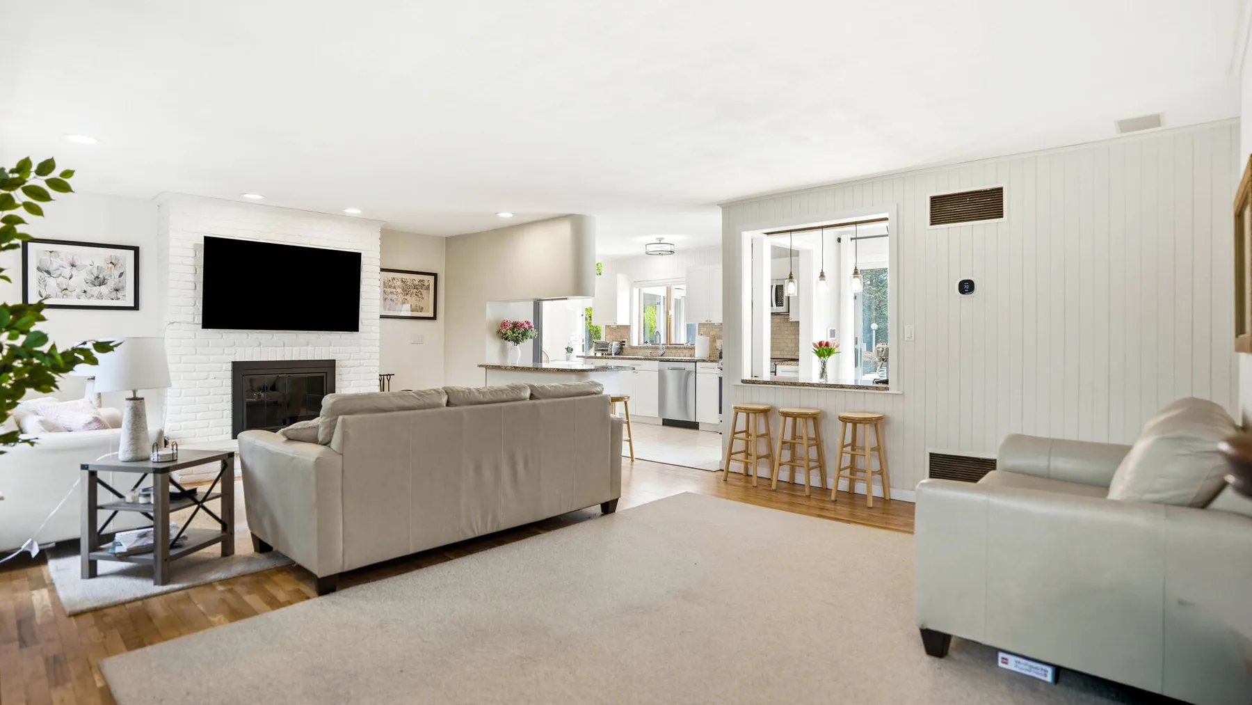 An open living room with seating, a television, and a kitchen bar.