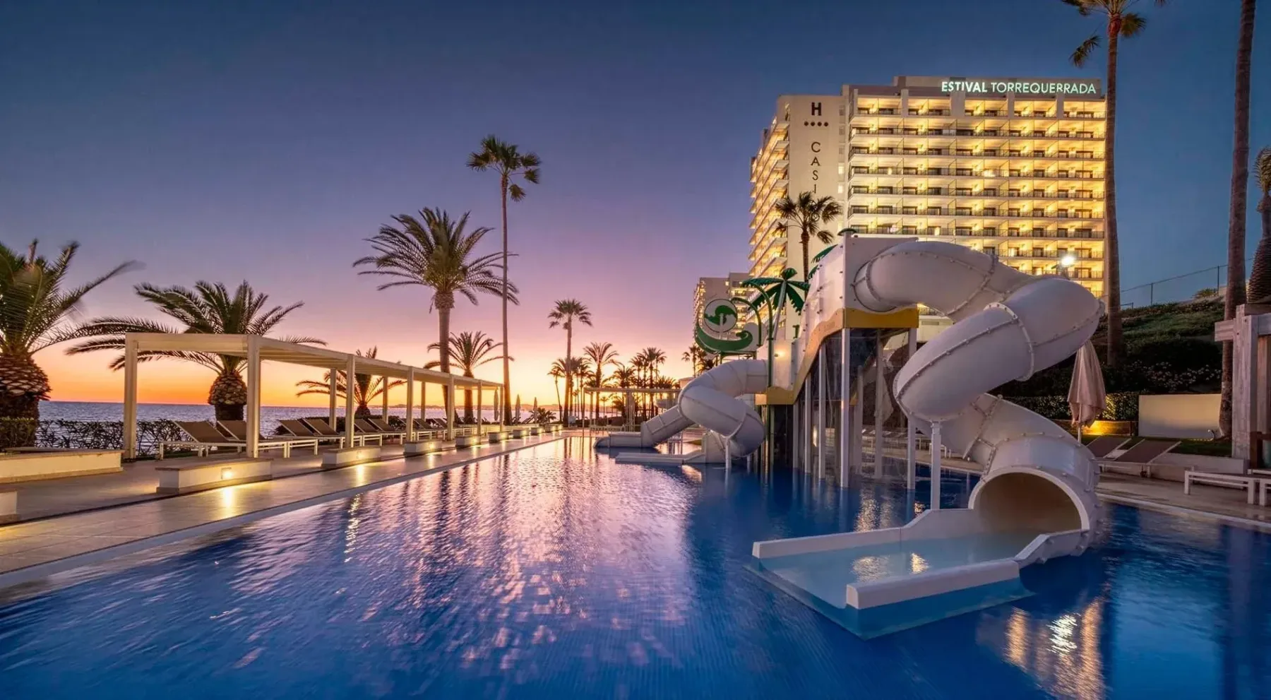 Pool with slides, palm trees and sunset