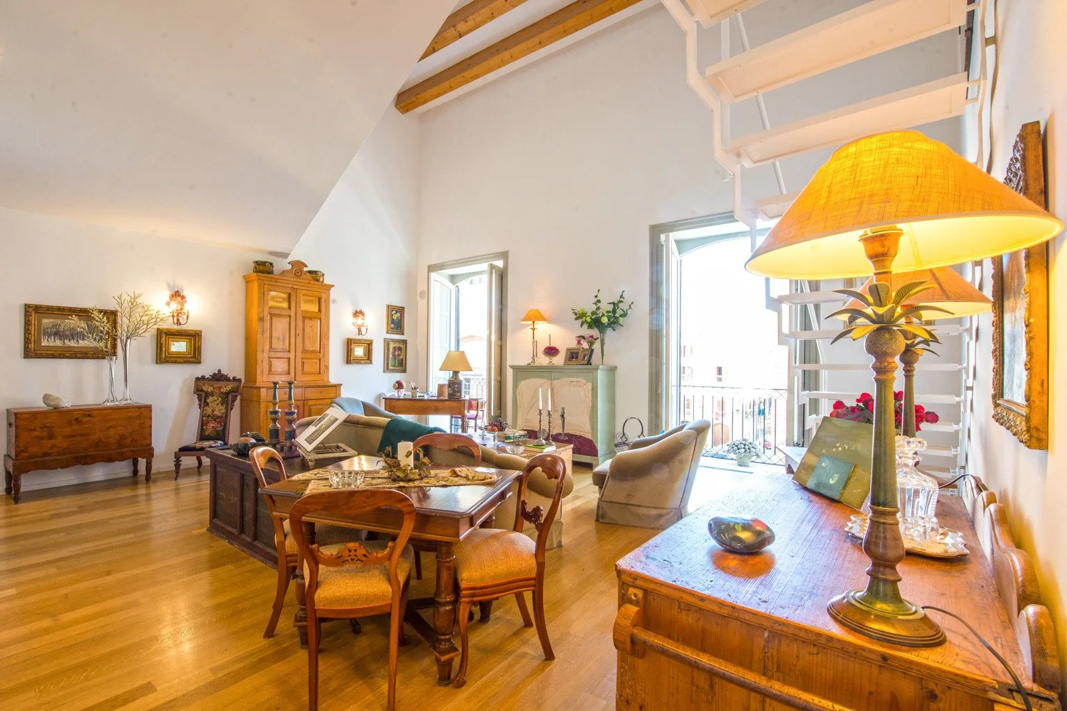 Una sala luminosa con suelo de madera, asientos y una mesa de comedor.