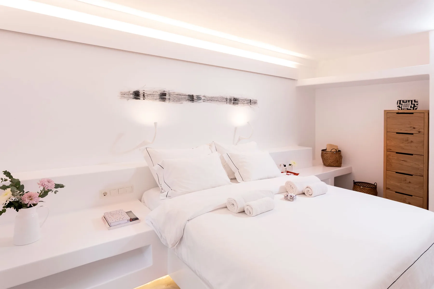 A bright bedroom with a neatly made bed and built-in bedside ledges.