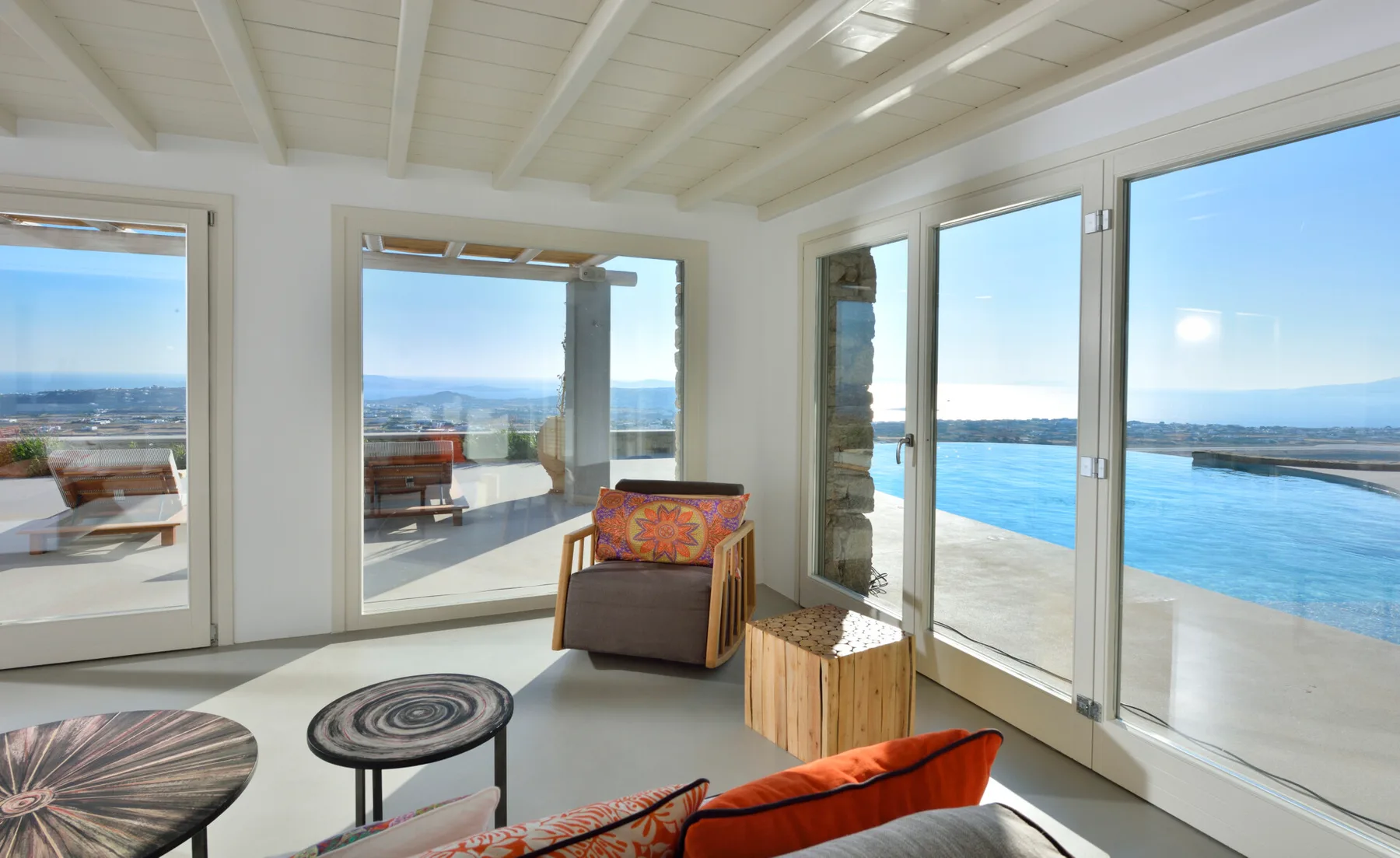 A bright living area opens onto a pool and distant coastal views.