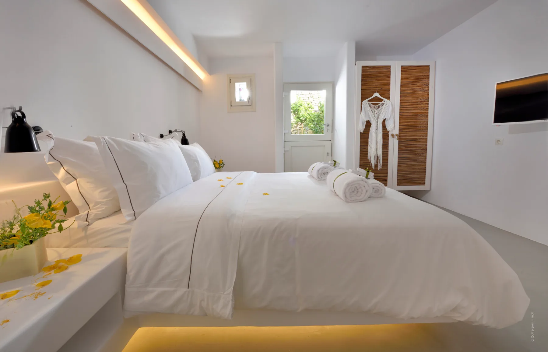 A bright bedroom with a large bed and a wall-mounted television.