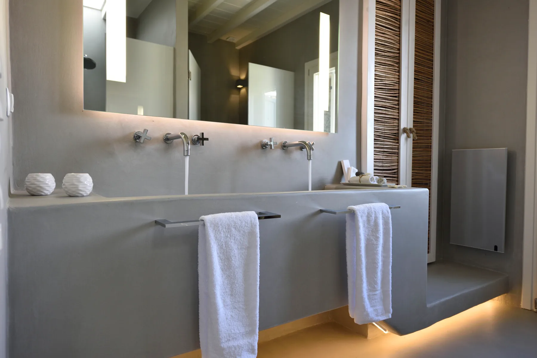 Bathroom vanity with two sinks and towels beneath a large mirror.