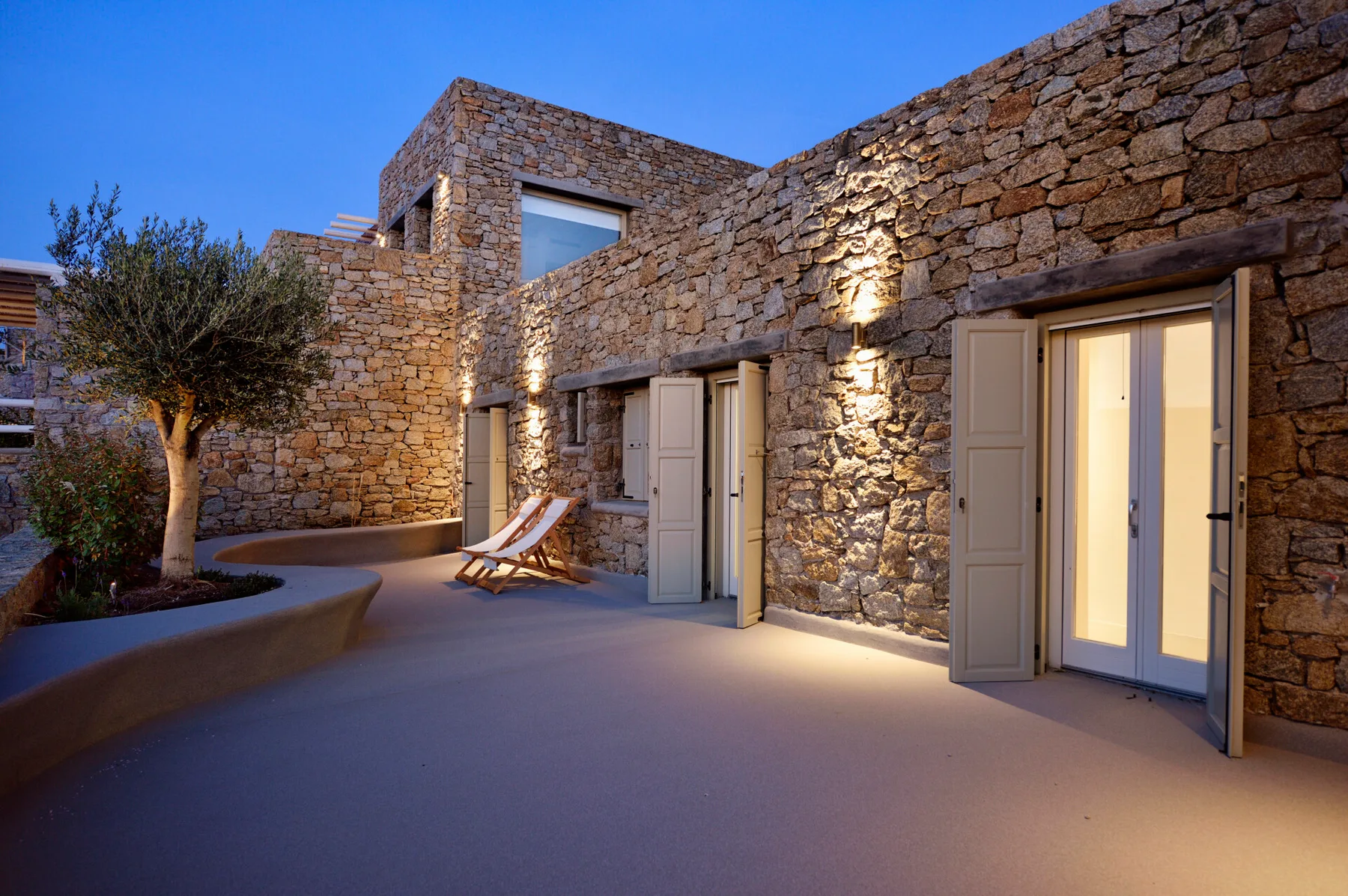 A stone courtyard with illuminated walls and lounge seating.
