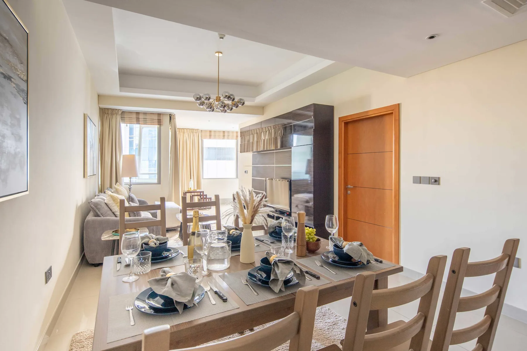 A dining area with a set table beside a living area and kitchen.