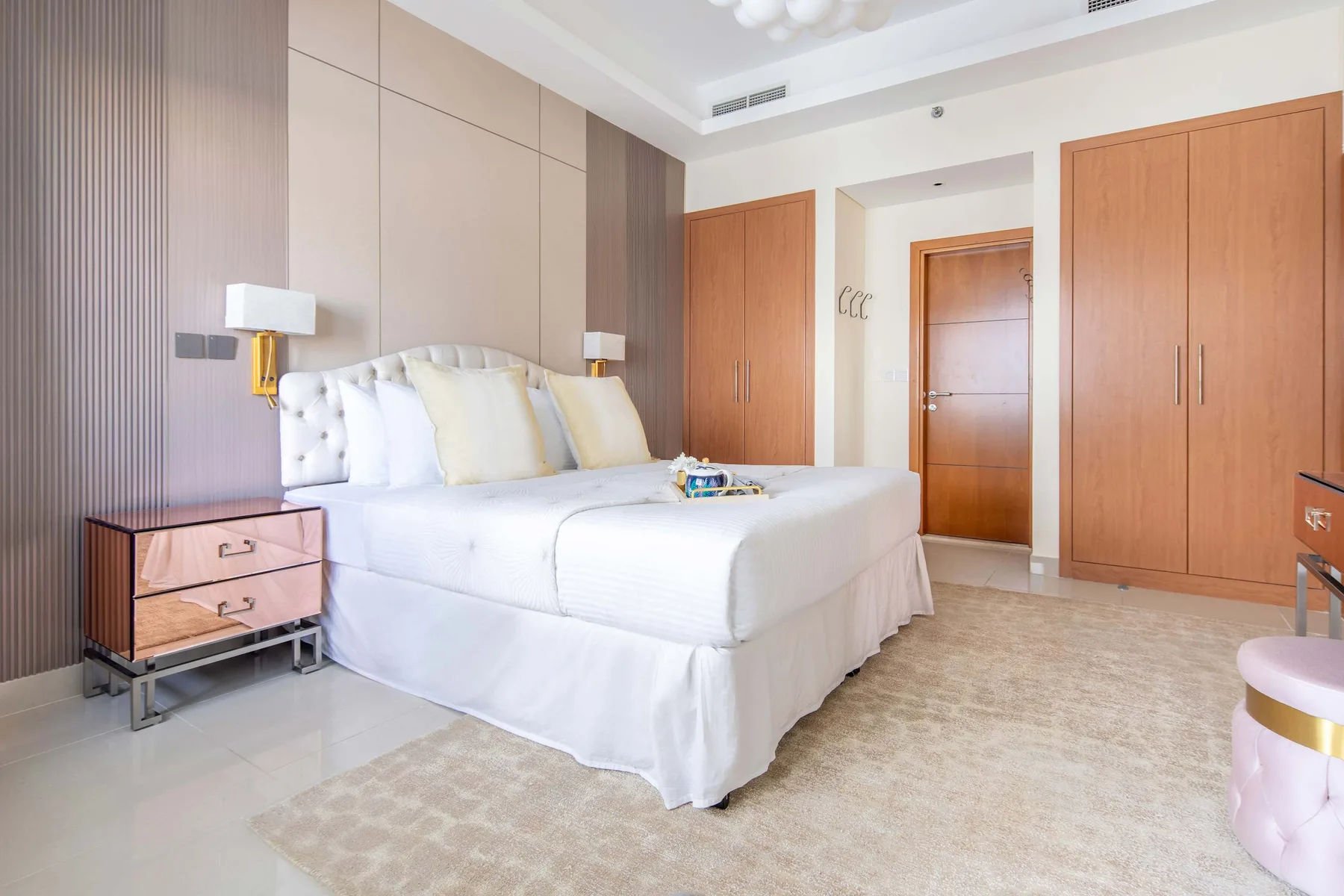 A bright bedroom with a large bed and built-in wooden wardrobes.