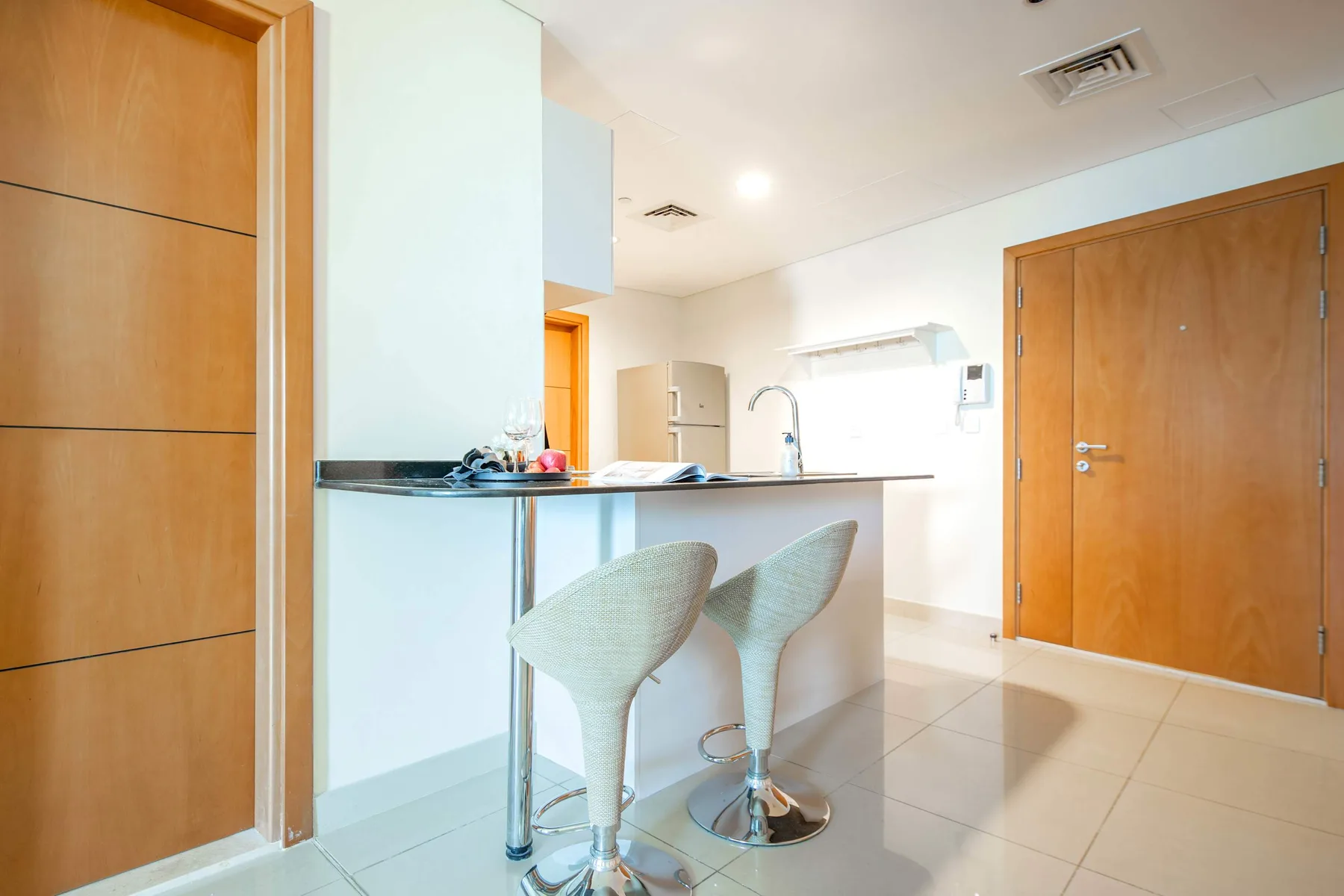 A bright kitchen with a counter and two stools.
