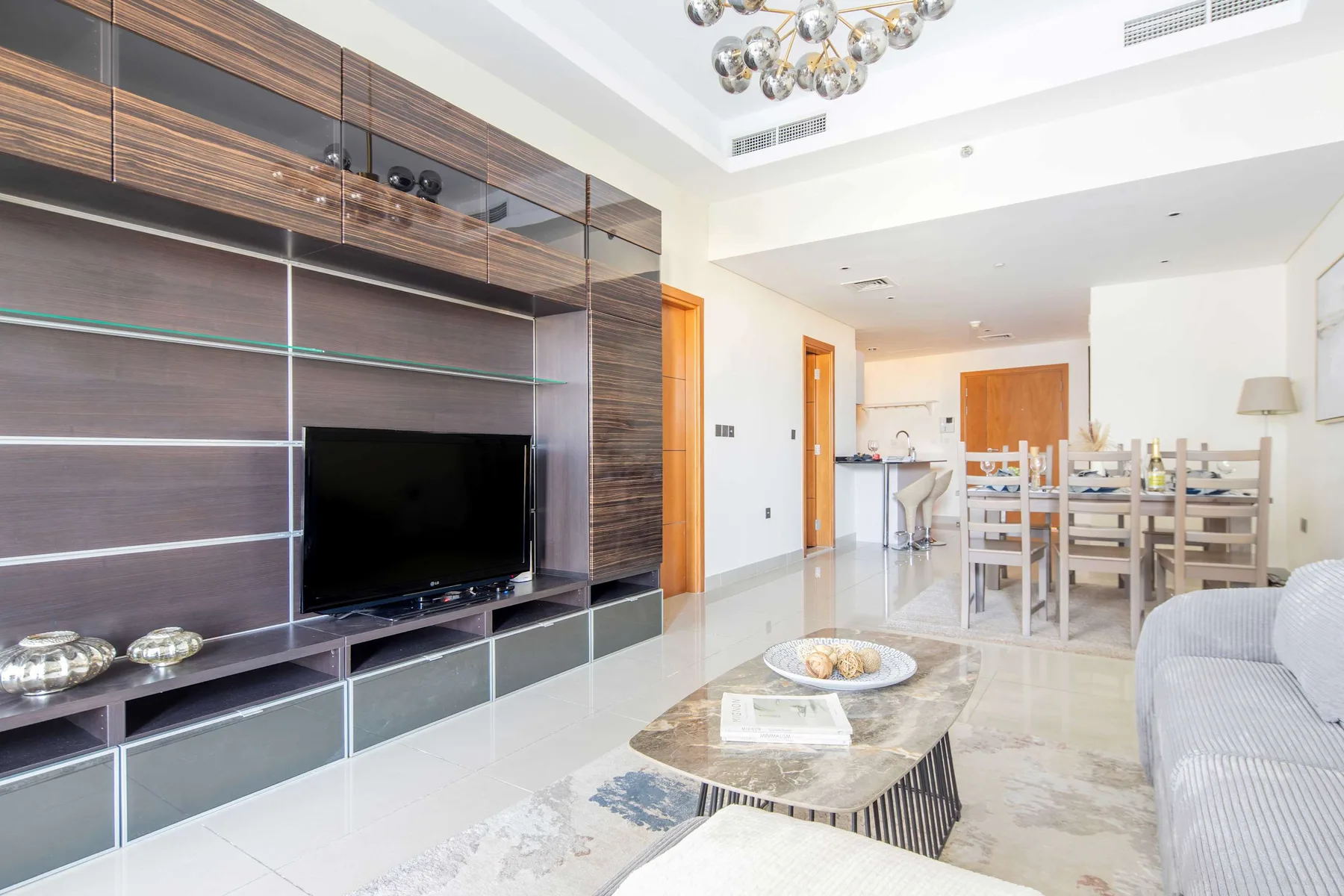 Una luminosa sala de estar y comedor cuenta con una pared con televisor y una mesa de comedor.