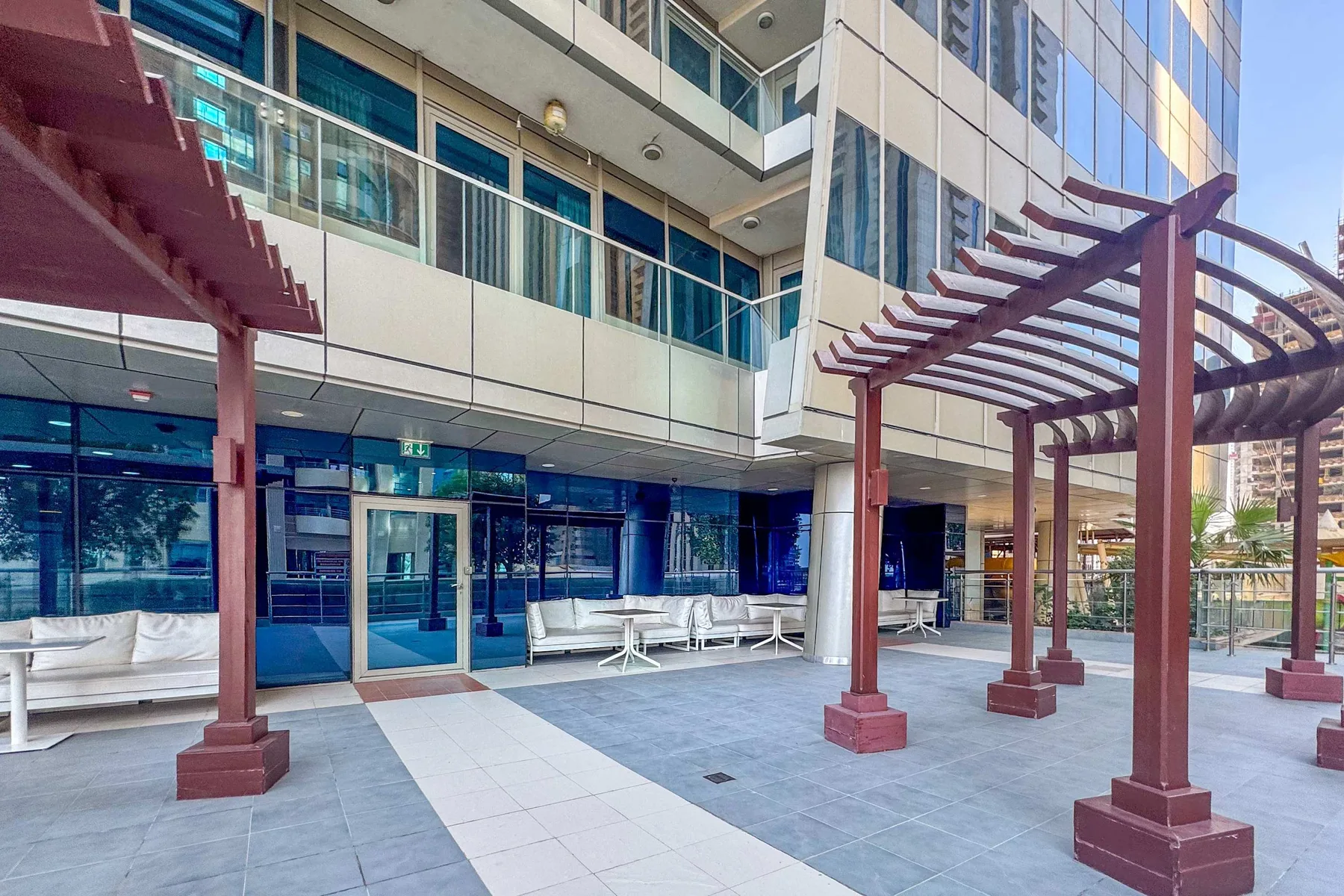A paved outdoor courtyard beside a modern building, with shaded seating areas.