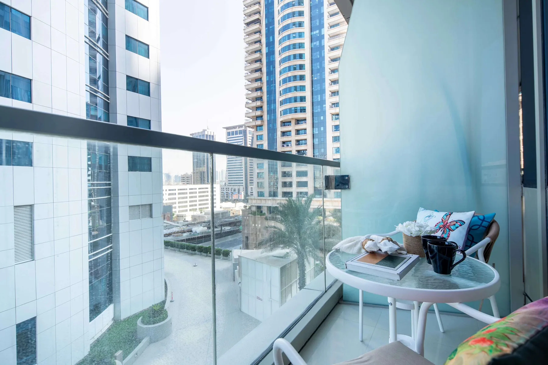 A small balcony seating area overlooks nearby high-rise buildings.