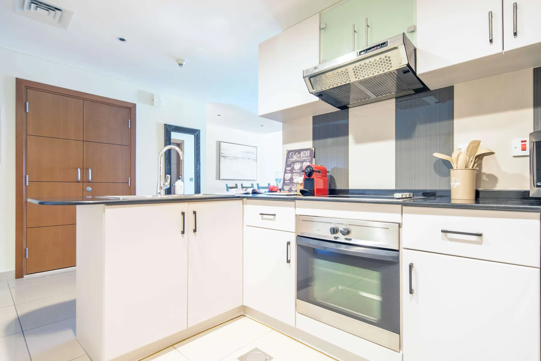 A modern kitchen with white cabinets, a built-in oven, and a dark countertop.