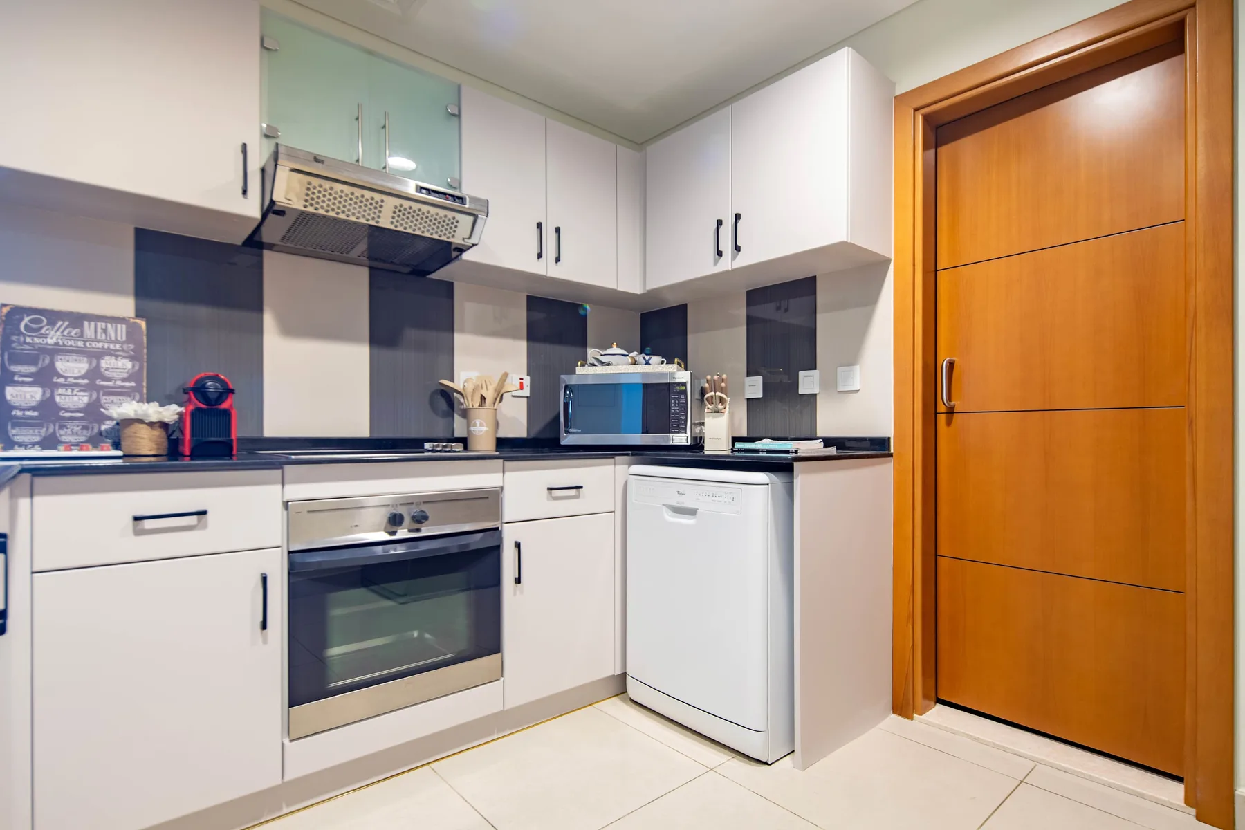 A compact kitchen with white cabinets, a countertop, and built-in appliances.