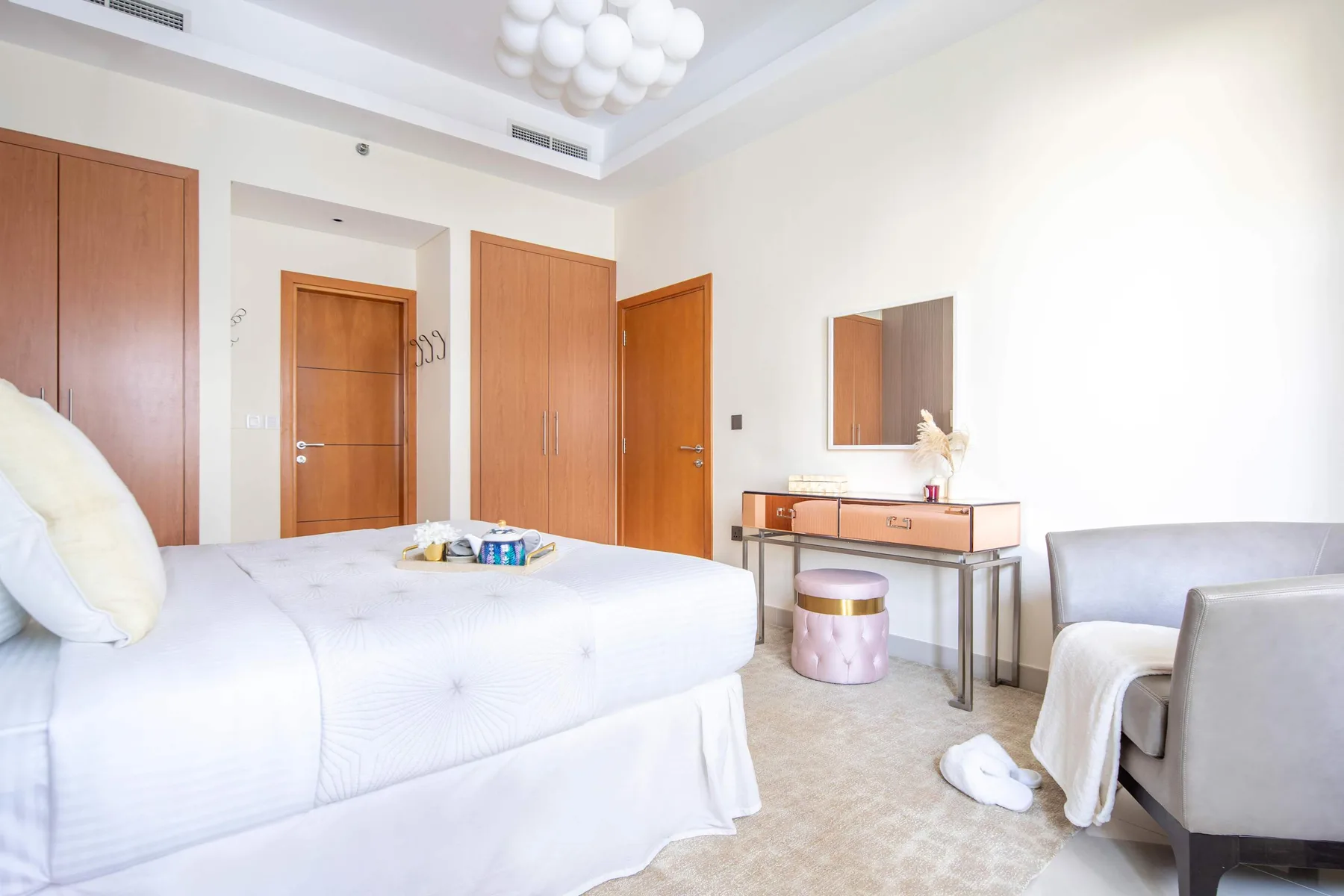 A bright bedroom with a large bed, a dressing table, and seating.