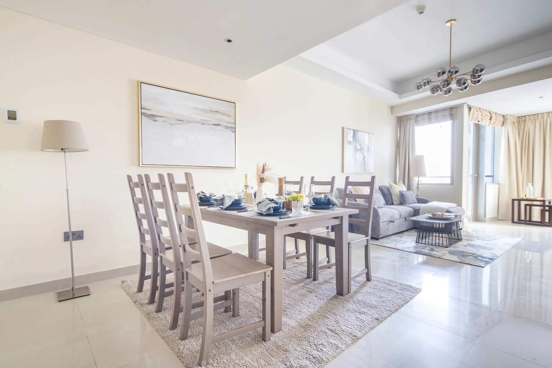 Una luminosa zona de comedor y estar con mesa, asientos y ventanas grandes.