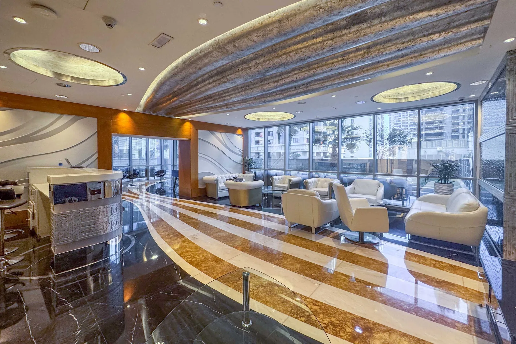 A modern lounge with seating arranged beside large windows.