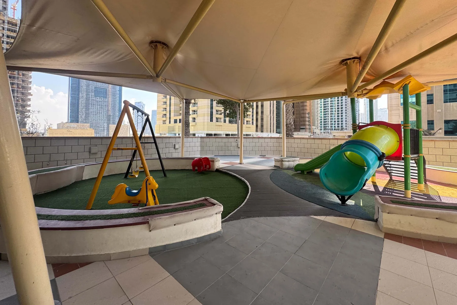 A covered rooftop playground has colorful slides and play equipment.