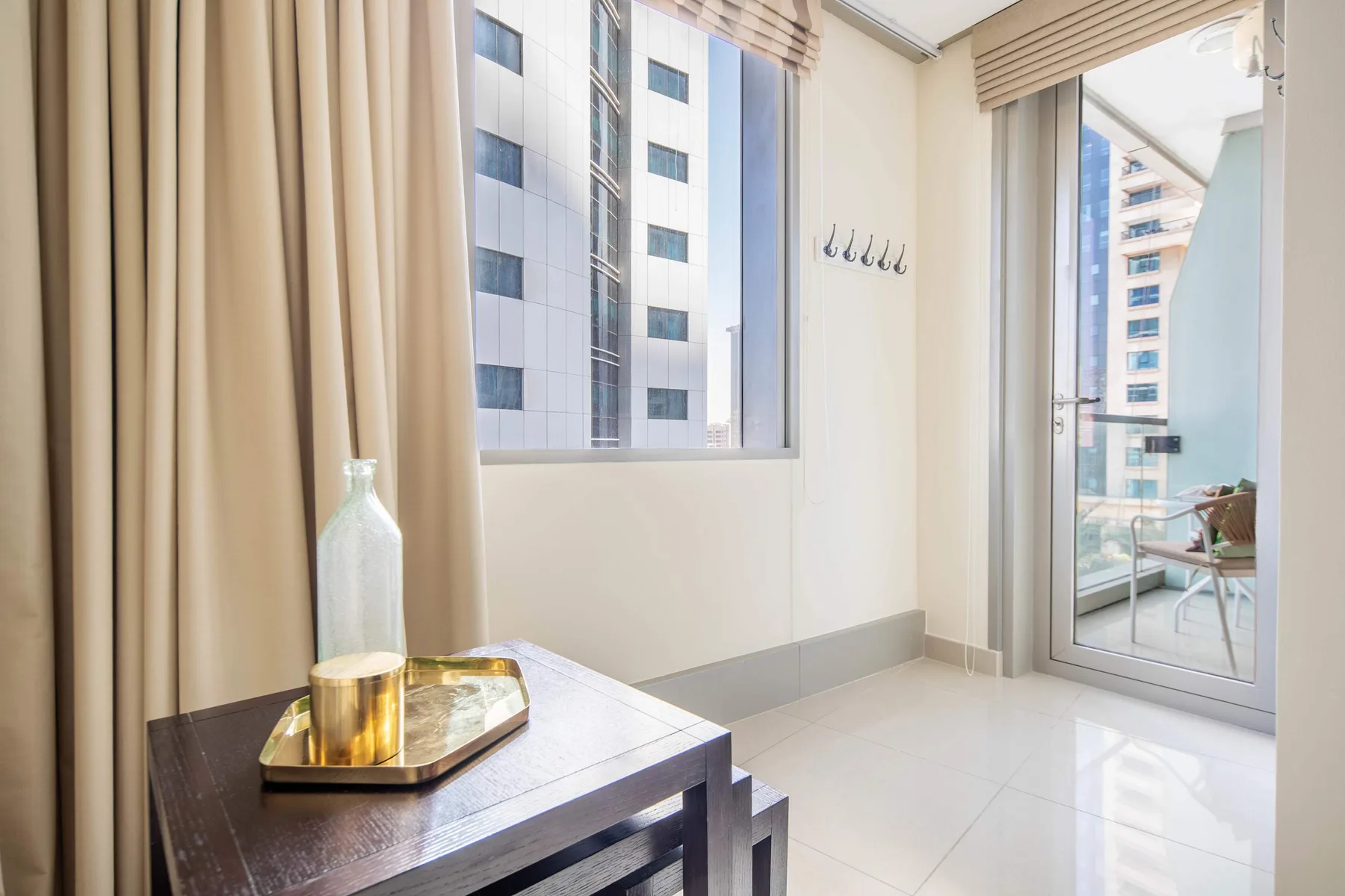 A bright room with a small table beside a window and glass balcony doors.