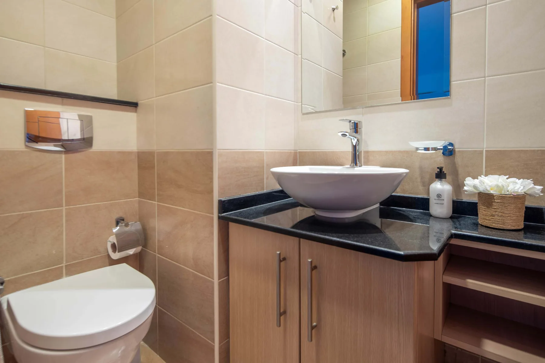 A tiled bathroom with a vessel sink, countertop, and toilet.
