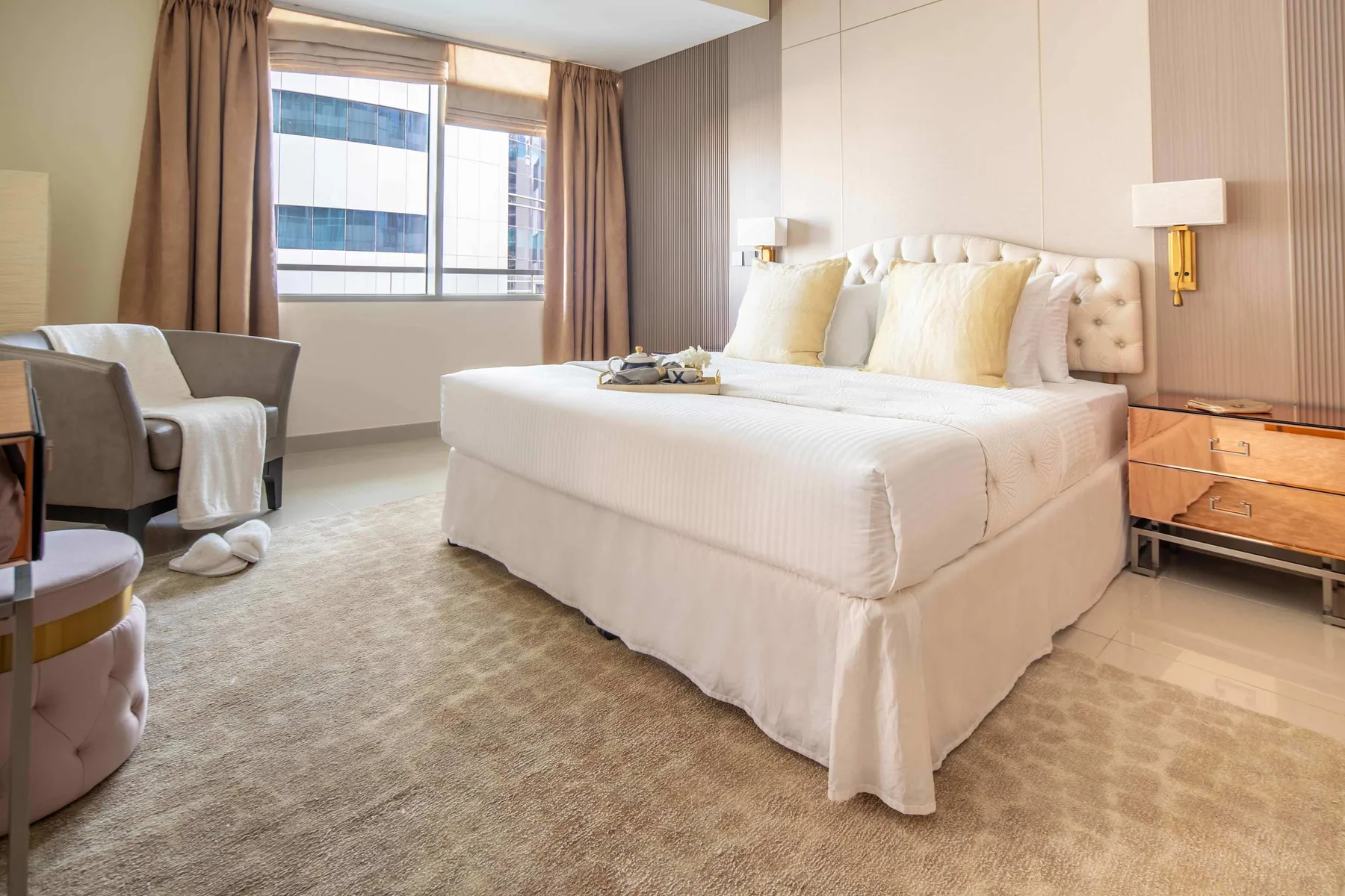 A bright bedroom with a large bed, bedside tables, and a window framed by curtains.