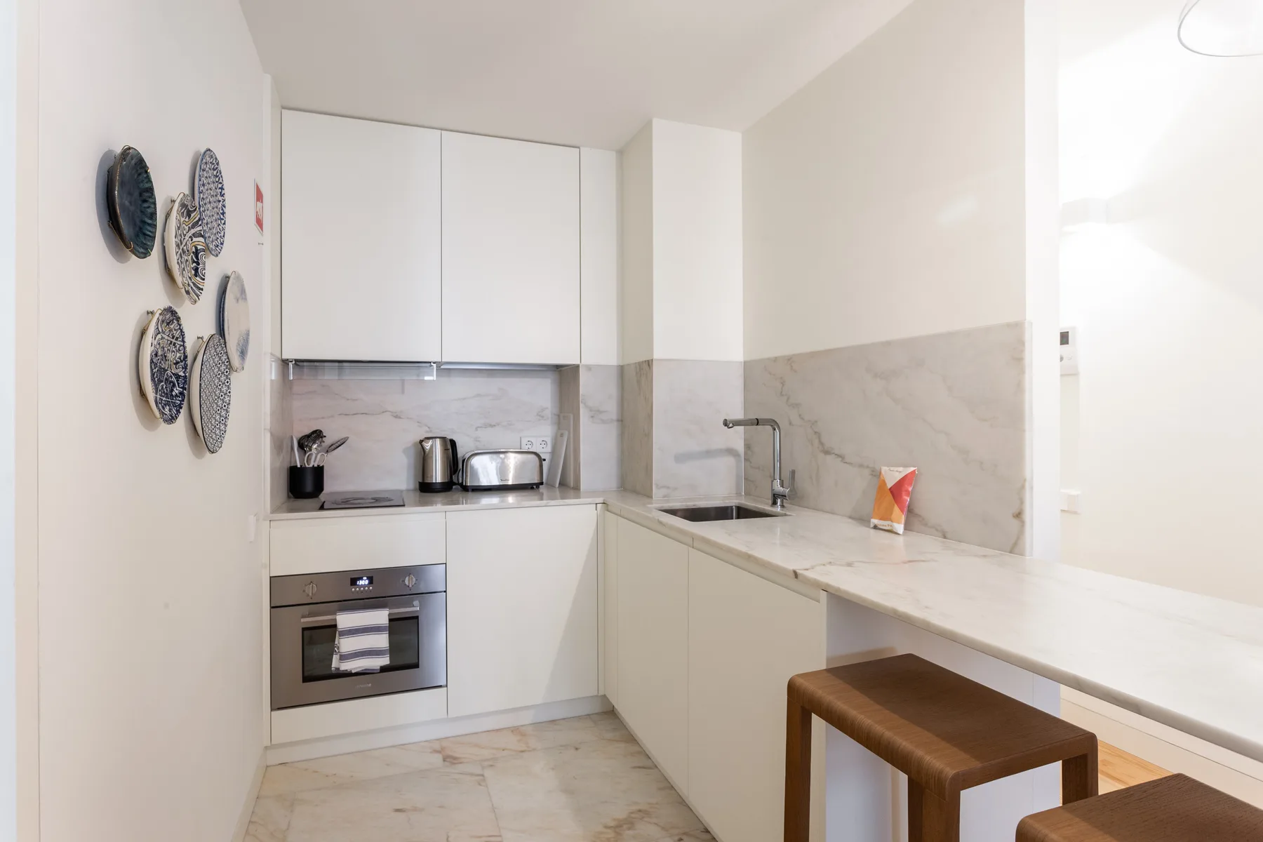 Una cocina compacta con armarios blancos, una encimera y una pequeña mesa de madera.