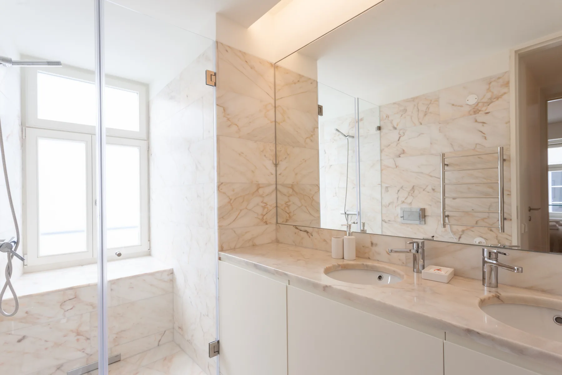 Un baño luminoso con ducha de vidrio y un amplio tocador.