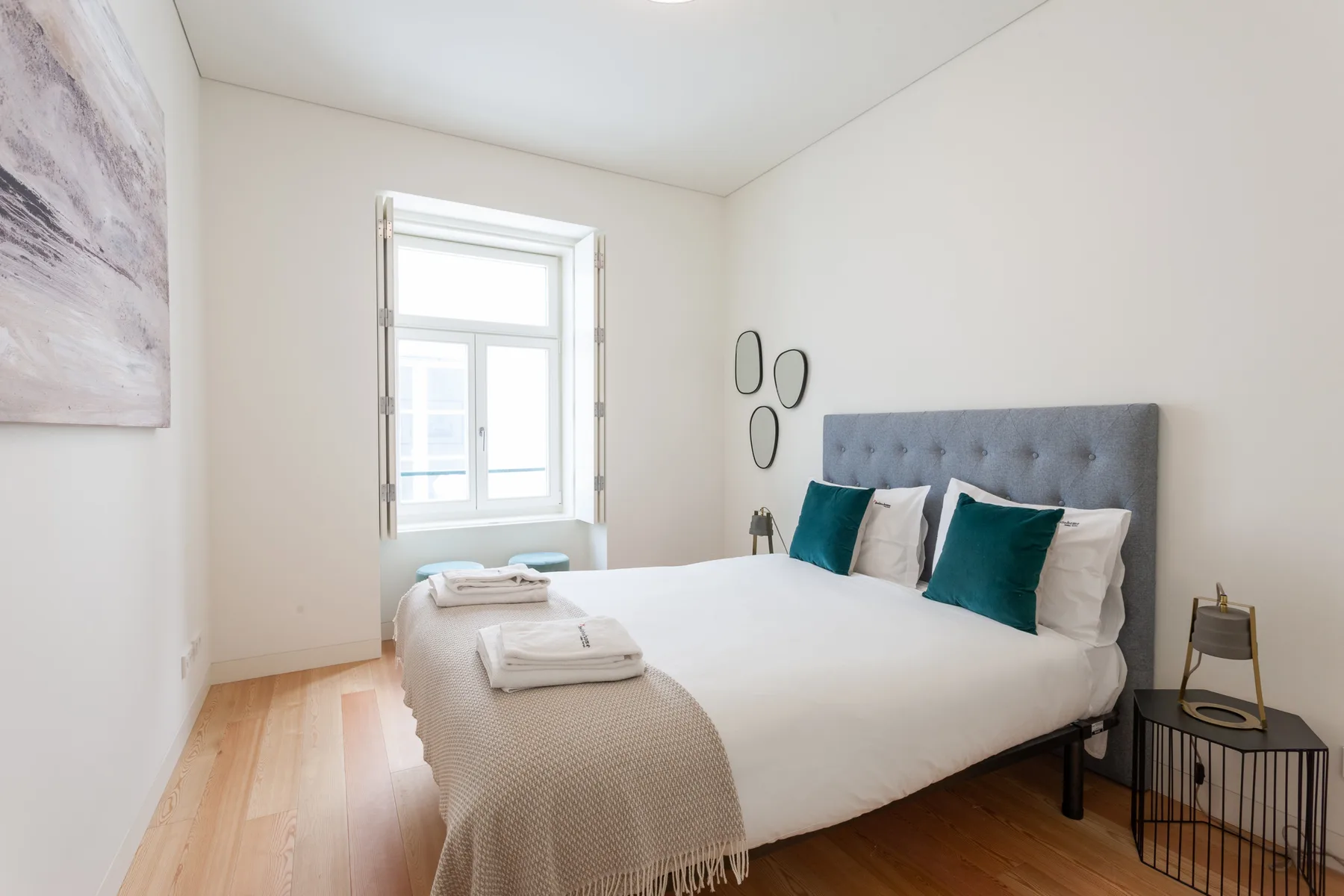 Un dormitorio luminoso con una cama bien hecha y una ventana.