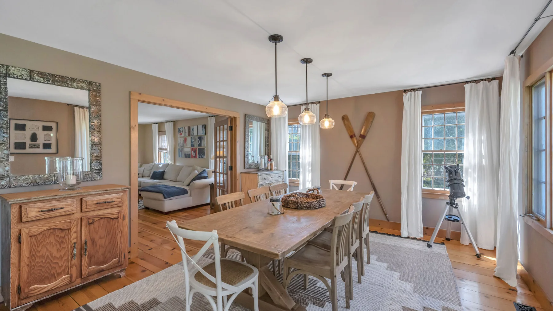 Comedor con una mesa de madera y sillas junto a ventanas amplias.