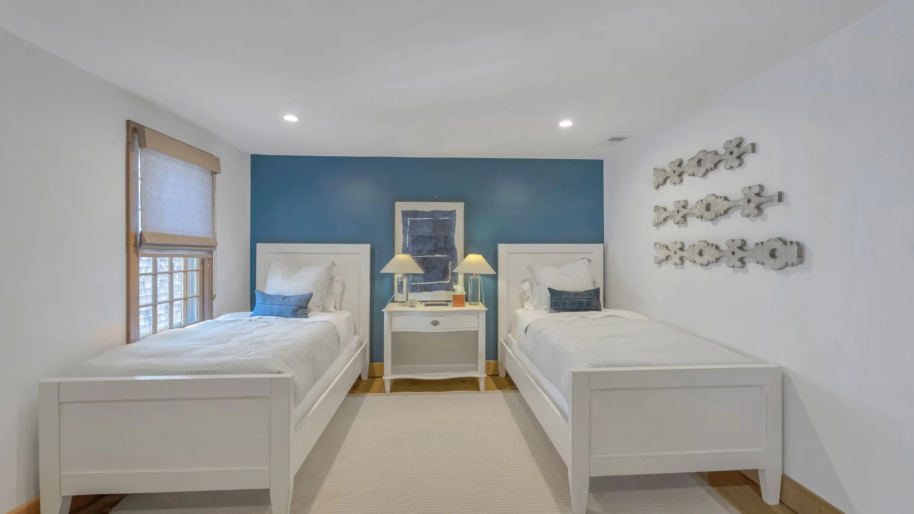 Un dormitorio con dos camas individuales, una mesita de noche y una pared azul.
