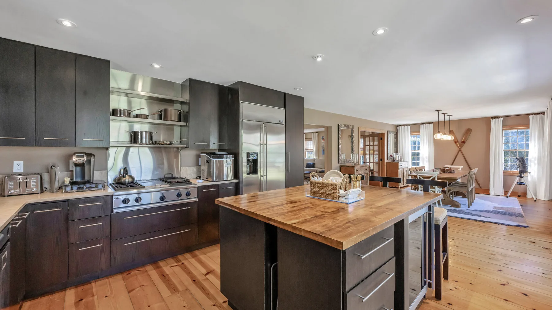 Una cocina abierta con gabinetes oscuros y una gran isla con cubierta de madera.