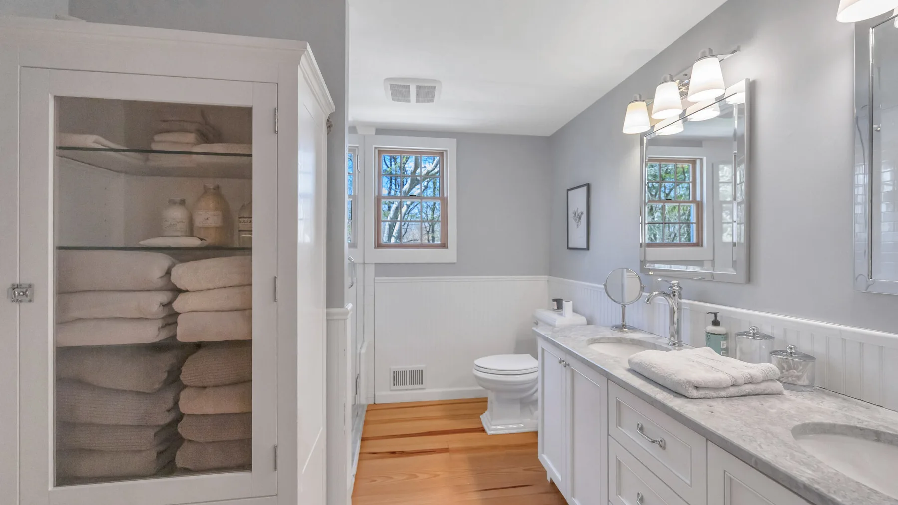 Un baño luminoso con un tocador largo, un espejo y una ventana.