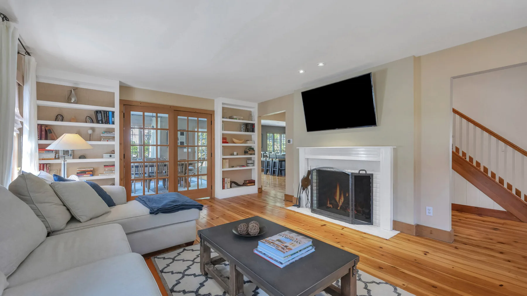 Una sala de estar con asientos, una chimenea y un televisor encima.