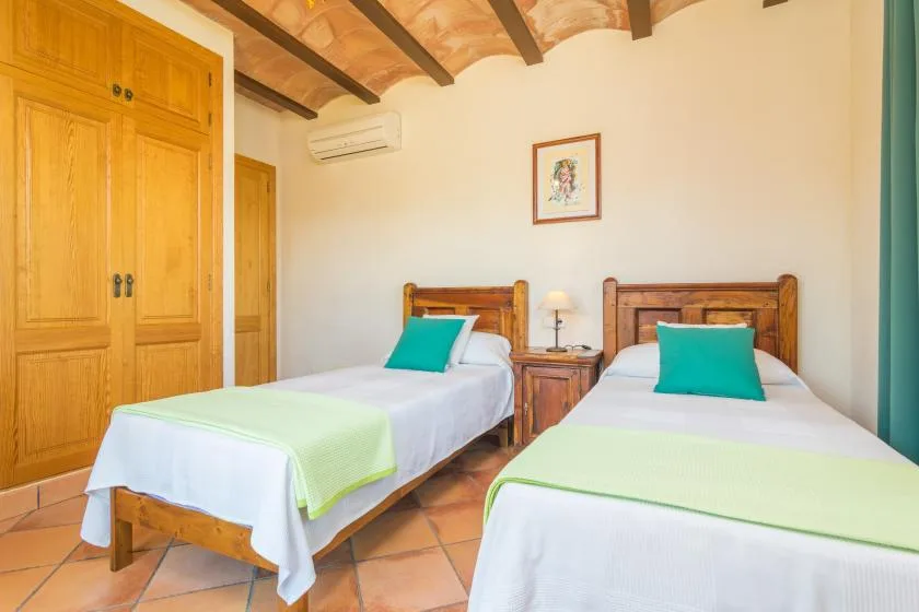 Un dormitorio con dos camas individuales, armarios de madera y vigas vistas en el techo.