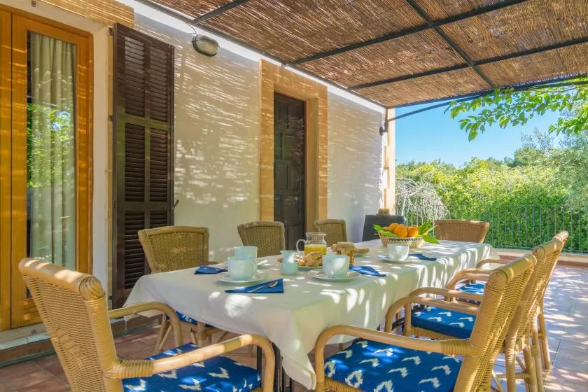Una zona de comedor al aire libre con una mesa larga y asientos tejidos.
