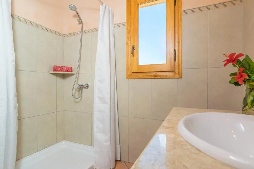 Un baño con ducha, ventana y lavabo.