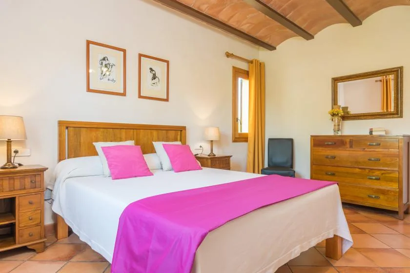 Un dormitorio con cama de madera, ropa de cama blanca y detalles en rosa intenso.