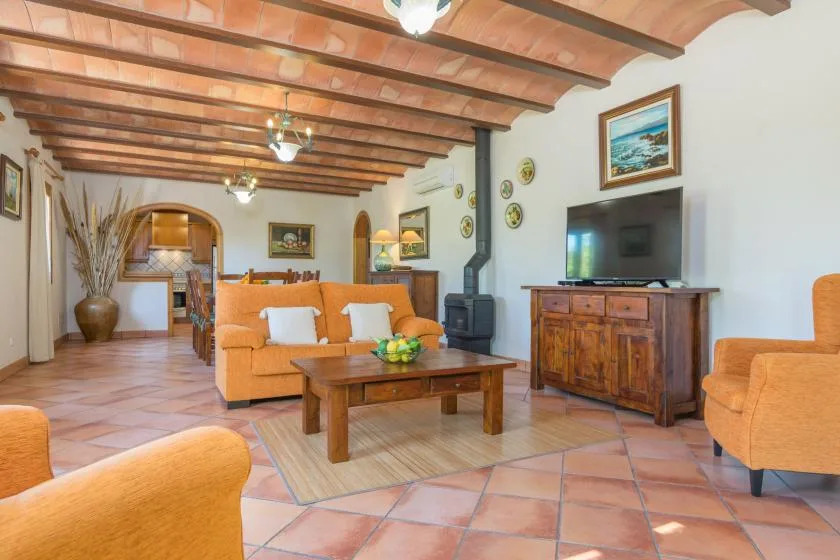 Una sala de estar con asientos naranjas, una mesa de centro de madera y vigas expuestas.