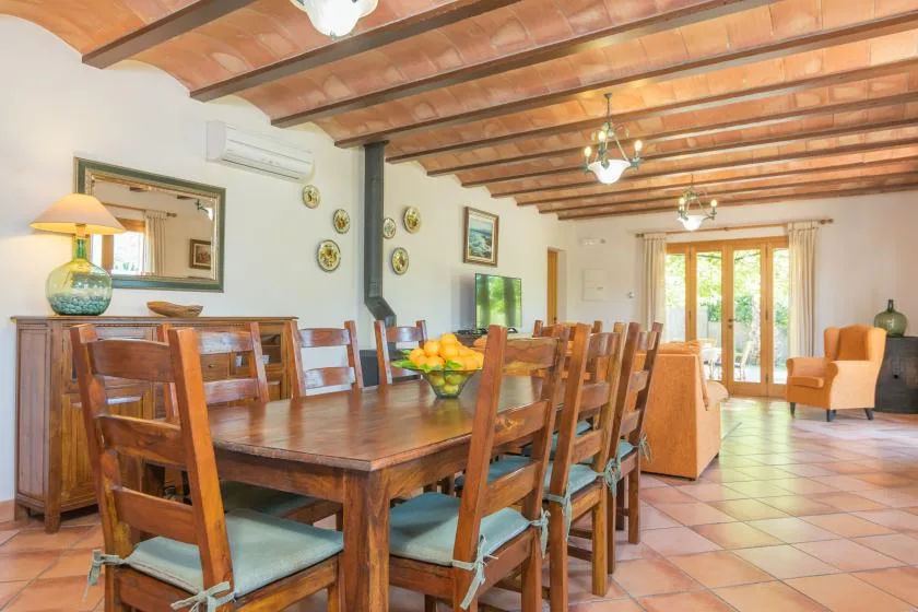 Un comedor con una mesa larga de madera y sillas bajo vigas de techo vistas.