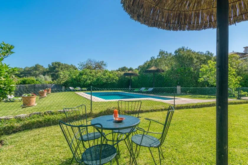 Una zona de estar en el jardín da a una piscina rodeada de vegetación.