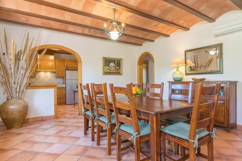Un comedor con una mesa y sillas de madera bajo vigas de techo expuestas.