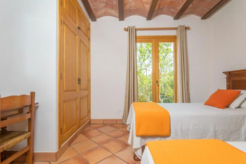 Un dormitorio con cama, armario de madera y una ventana con vista a la vegetación.