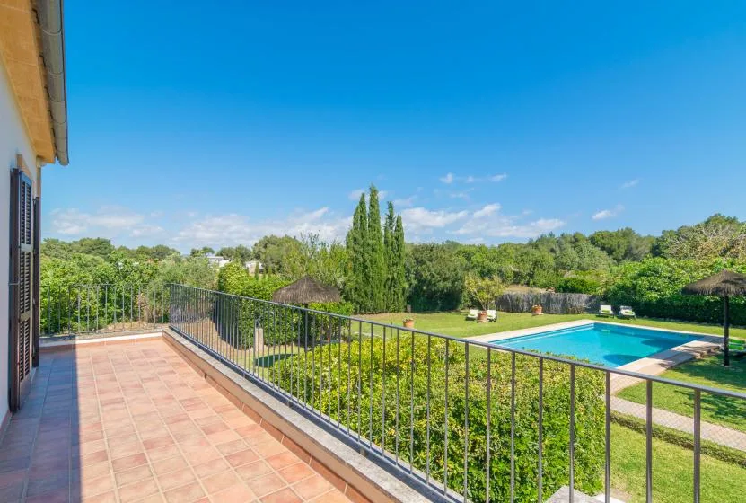 Una terraza de baldosas da a una piscina cercada y zonas verdes.