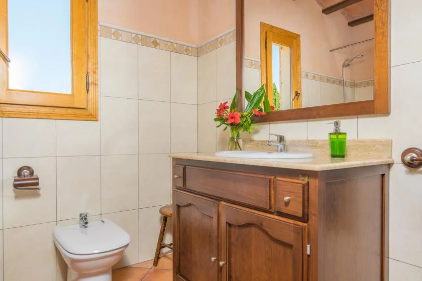 Un baño alicatado con mueble de madera, lavabo y espejo.