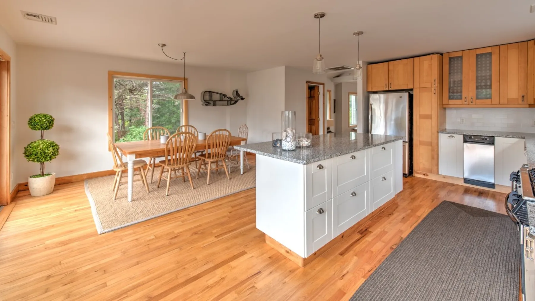 Una cocina y comedor abiertos, con una isla central y una mesa junto a la ventana.