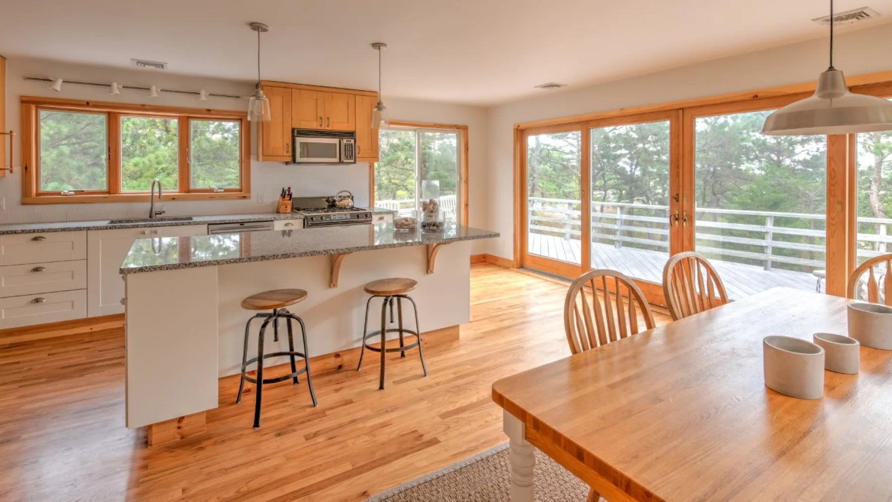 Una cocina y comedor luminosos con una isla central y grandes ventanas.