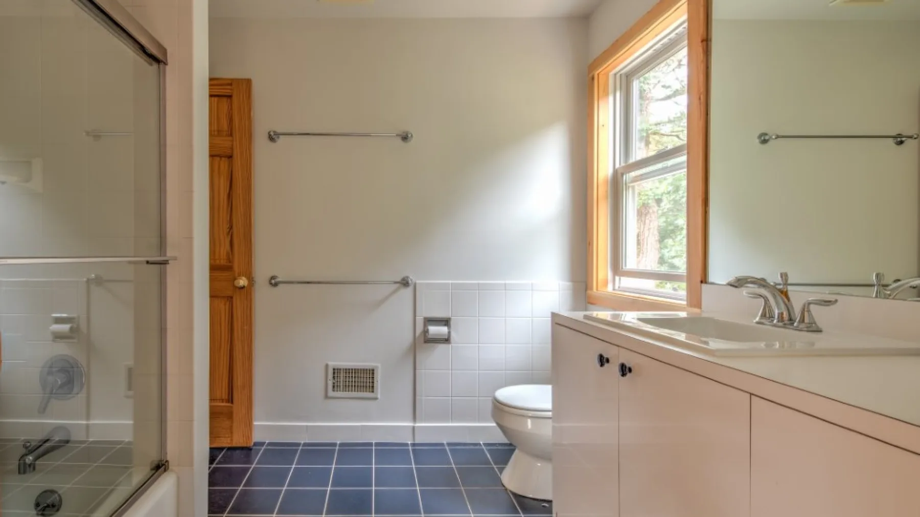 Un baño con ducha de vidrio, un tocador y una ventana.