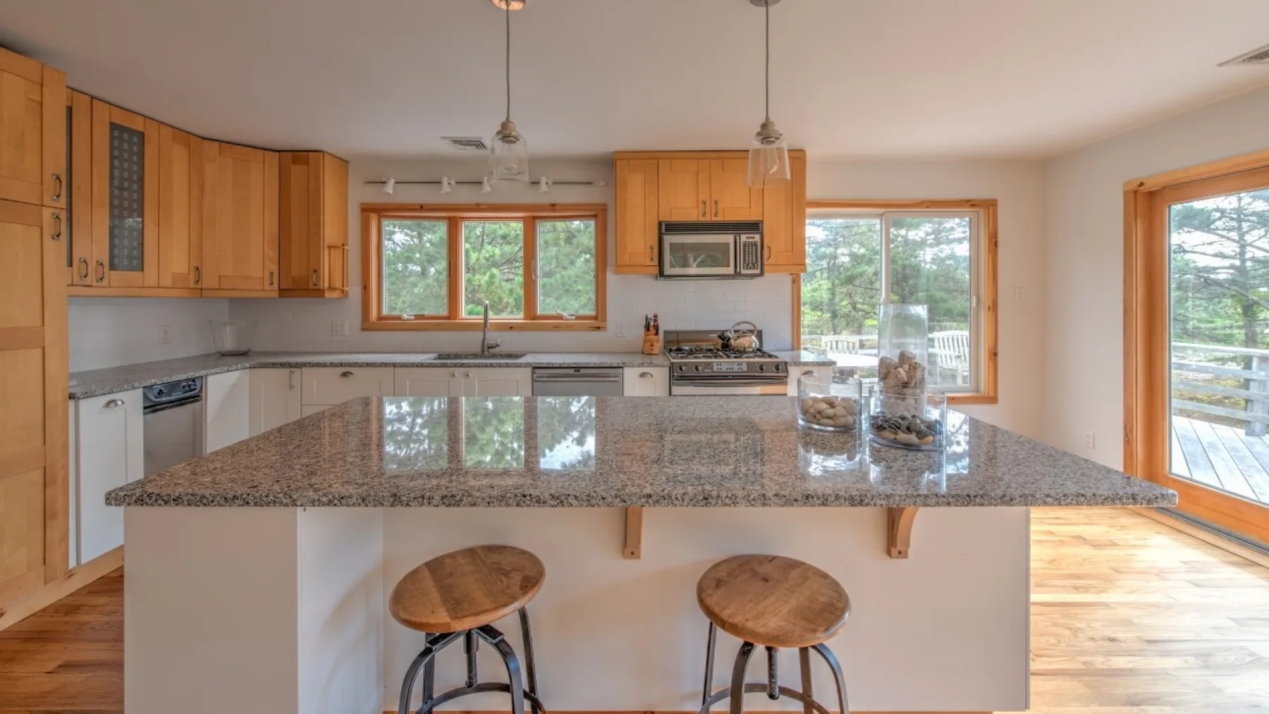 Una cocina luminosa cuenta con una isla grande de superficie de piedra pulida y asientos.