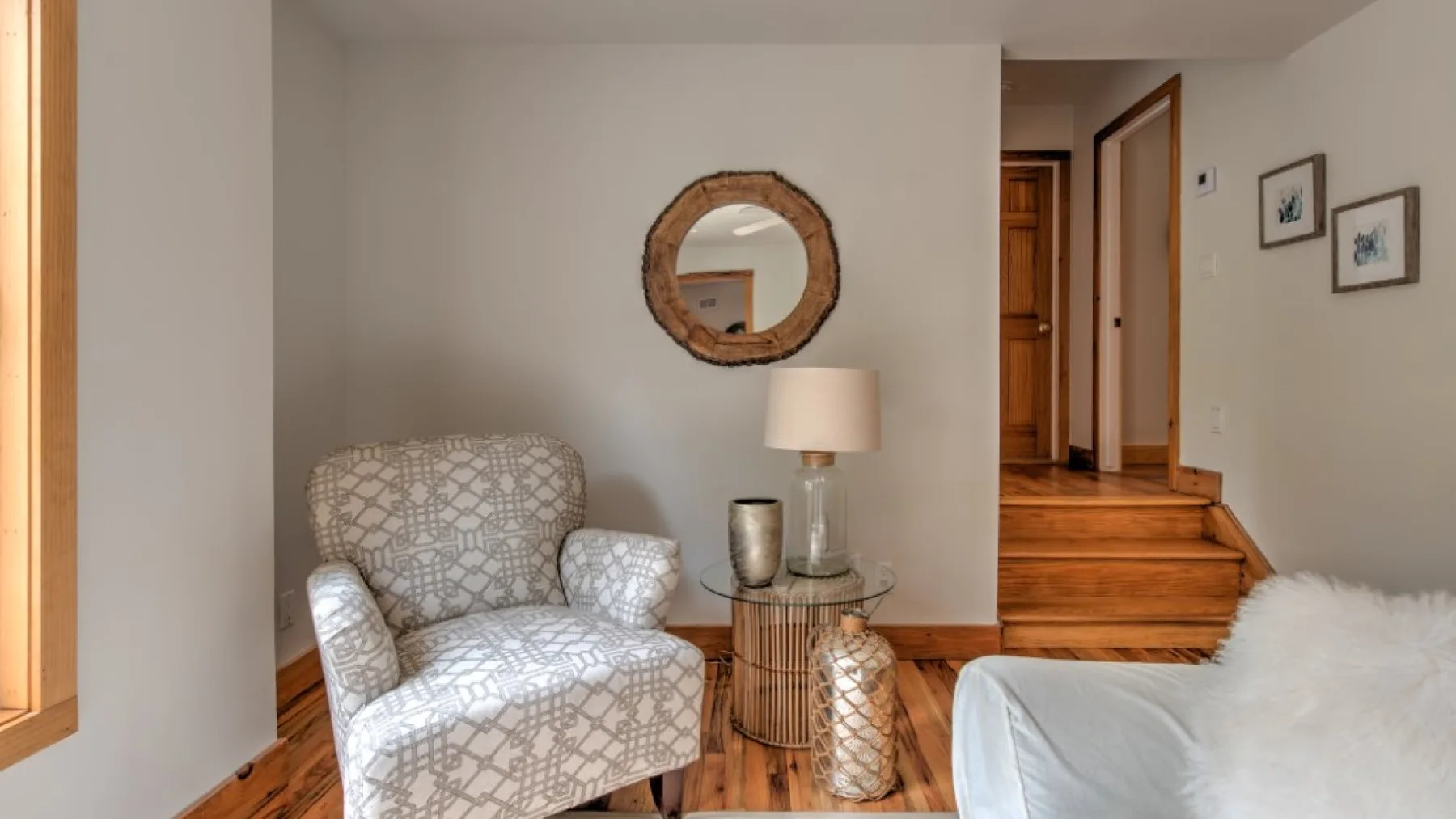 Una zona de estar en un dormitorio, con un sillón estampado junto a la cama.