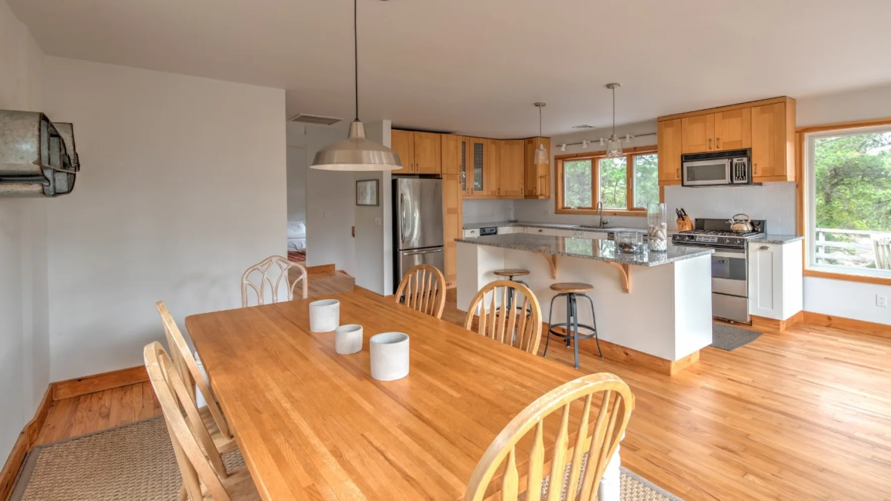 Un comedor se abre a una cocina con gabinetes de madera e isla central.